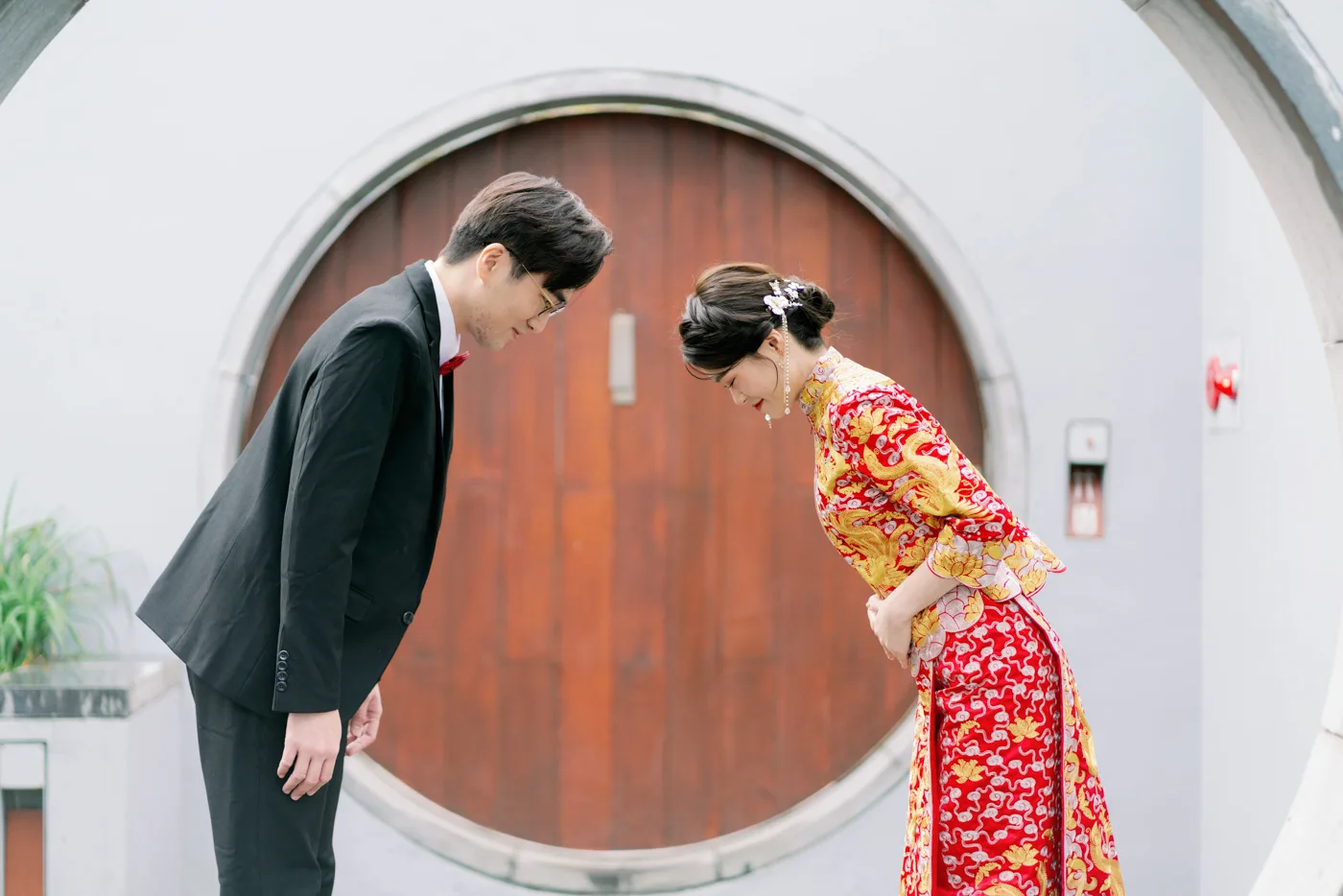 作品:穿中式禮服的新娘與新郎在圓門前互相鞠躬